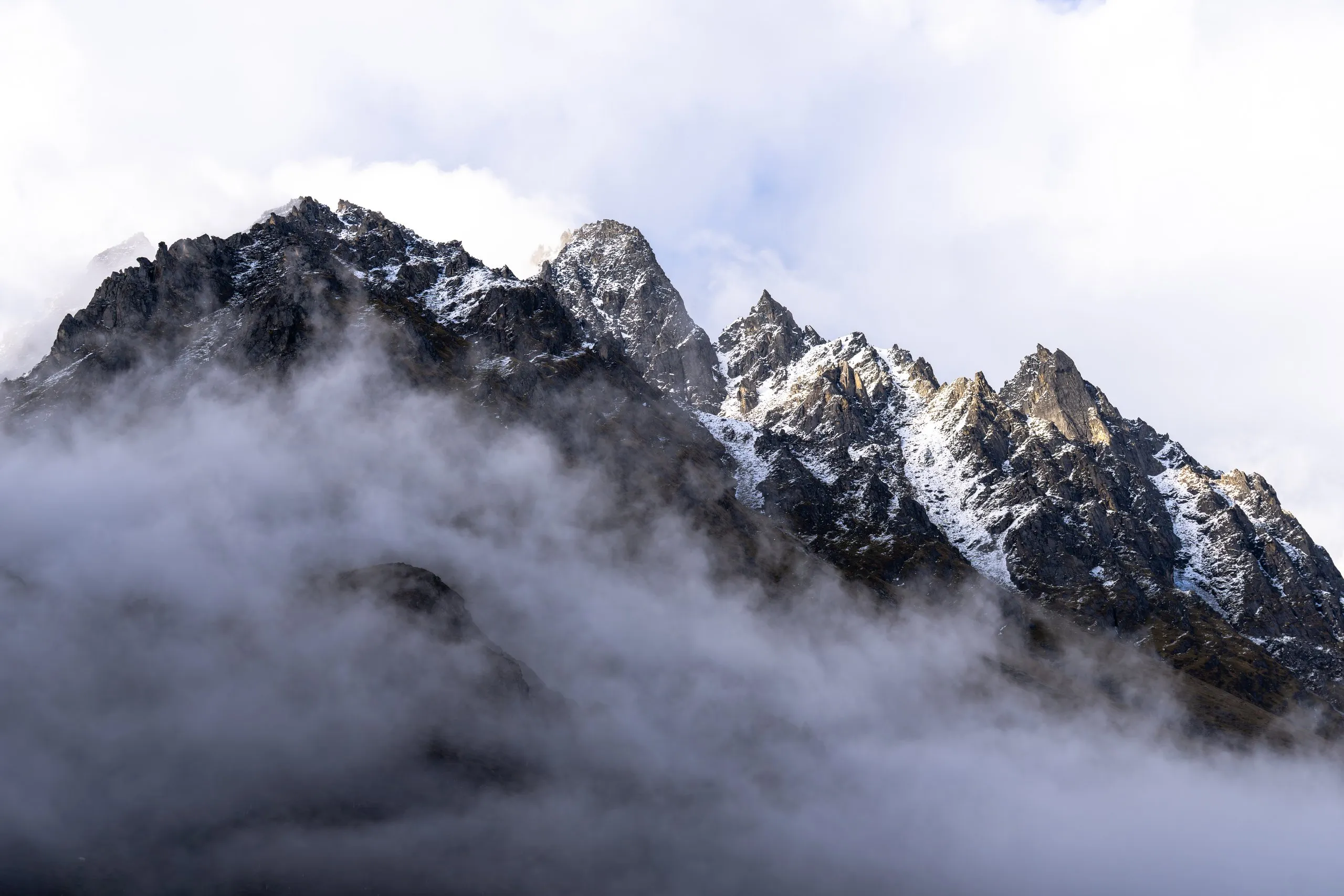 Jagged snow-dusted Himalayan peak breaking through a sea of clouds, Bhutan